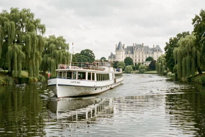 Bateau de croisière fluviale naviguant sur la Loire avec des châteaux en arrière-plan et des rives verdoyantes